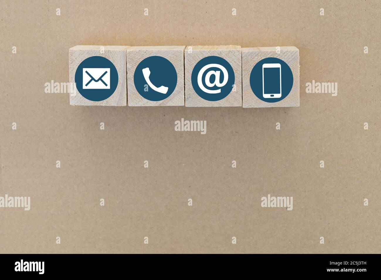 Holzwürfel mit Telefon, Email und Post Icons auf braunem Papierhintergrund. Kopierraum. Kontaktieren Sie uns. Stockfoto