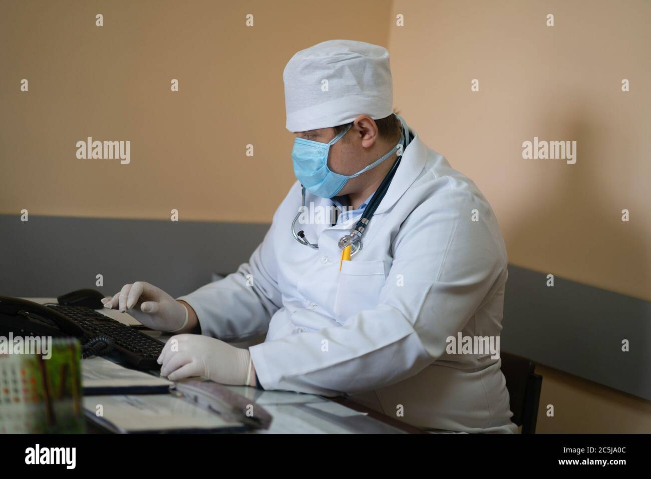 GP Arzt arbeitet mit Computer in der medizinischen Praxis. Heilpraktiker, der am Schreibtisch sitzt und auf der Tastatur tippt. Stadtkrankenhaus. Mai 2020 Stockfoto