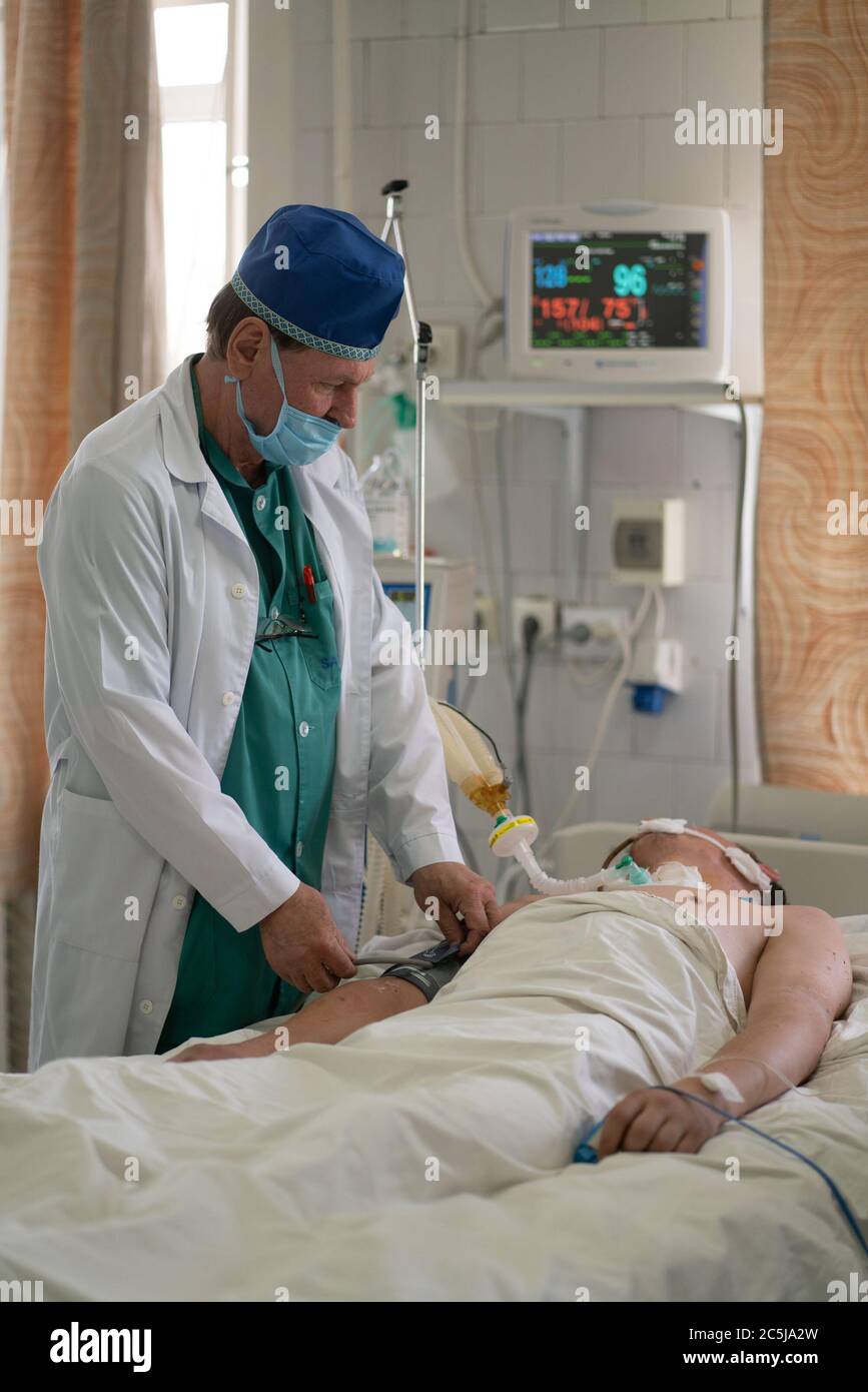 Arzt untersucht schwerkranken Patienten. Mann nach der Operation ist auf der Intensivstation. Stadtkrankenhaus. Mai 2020, Brovary, Ukraine Stockfoto