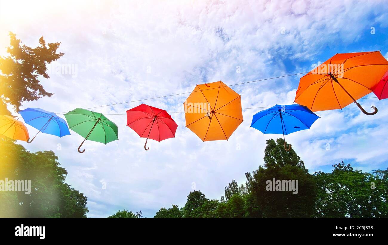 Bunte Regenschirme Hintergrund. Helle bunte Regenschirme am Himmel. Straßendekoration mit Sonnenschirmen. Stockfoto