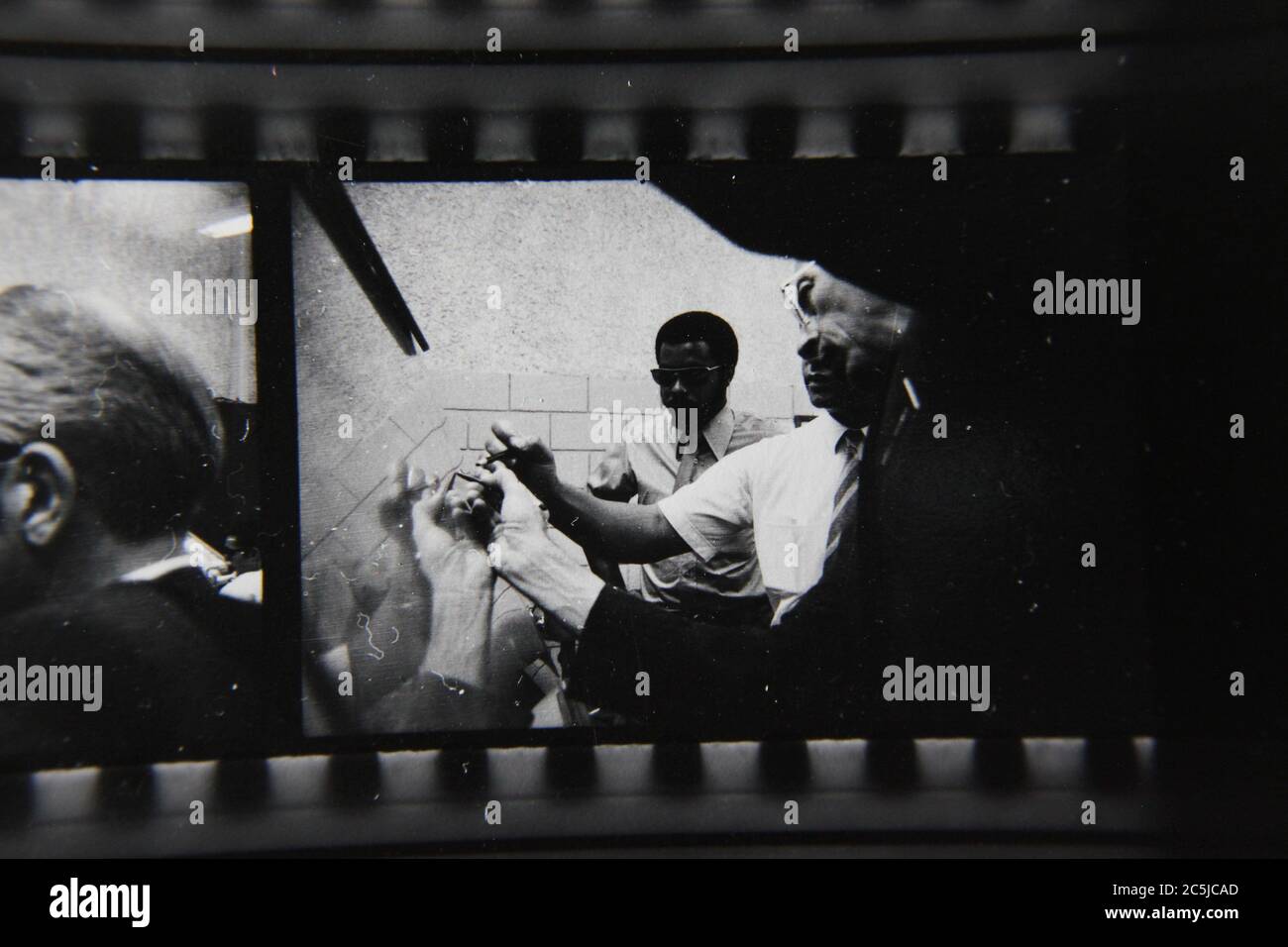 Feine 70er Jahre Vintage Kontakt Print schwarz-weiß Fotografie einer Gruppe von Mitarbeitern diskutieren Strategie zur Lösung eines Problems. Stockfoto