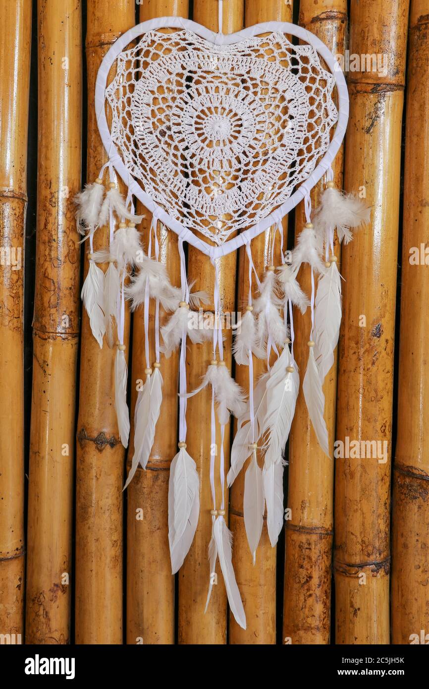 Traumfänger-Herz mit beigen Pfauenfedern an der Bambuswand Stockfotografie  - Alamy