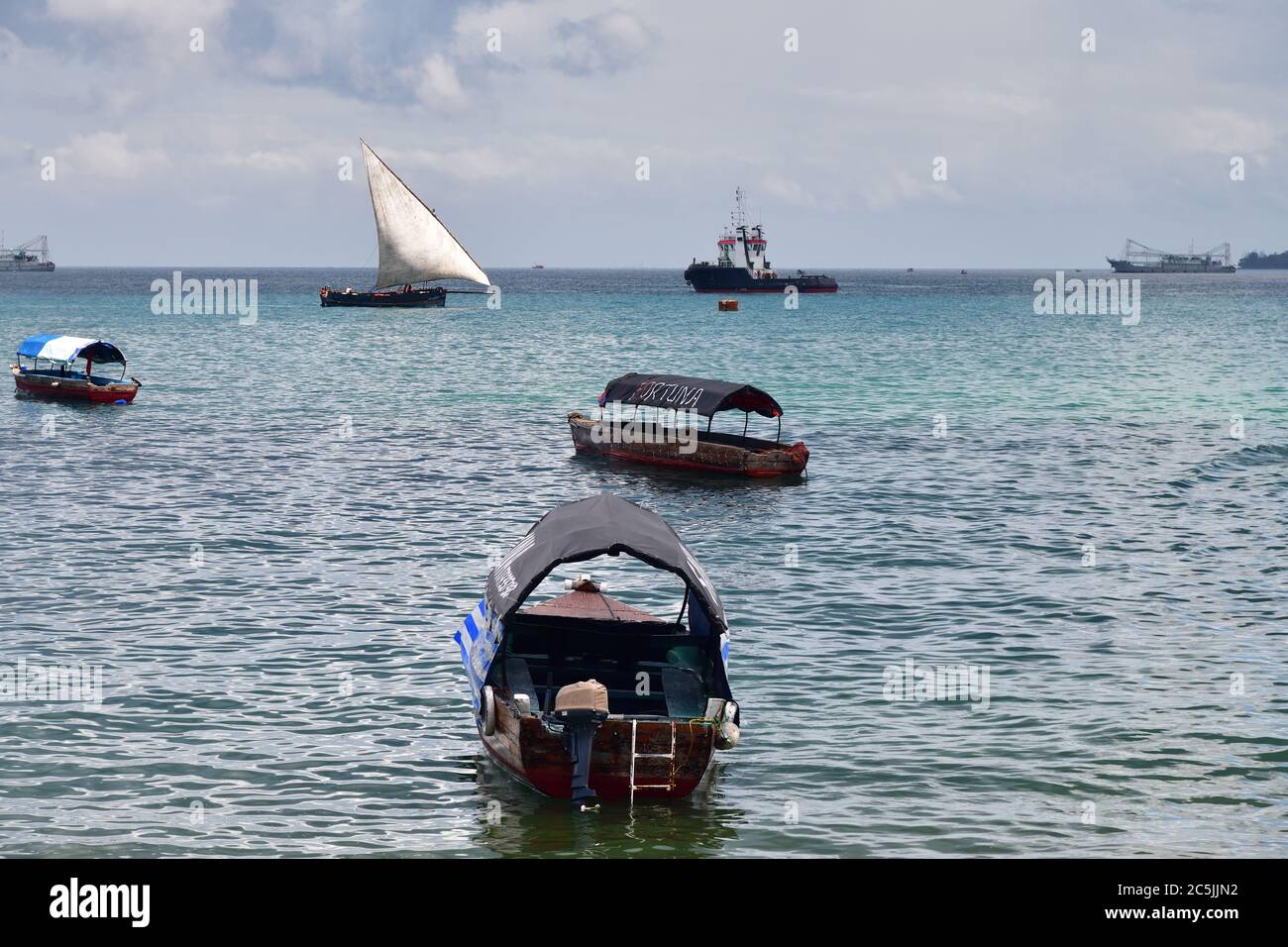 Sansibar, Tansania - 7. Oktober 2019: Dhow-Segelboot und andere Schiffe im Hafen von Stone Town, Sansibar, Afrika Stockfoto