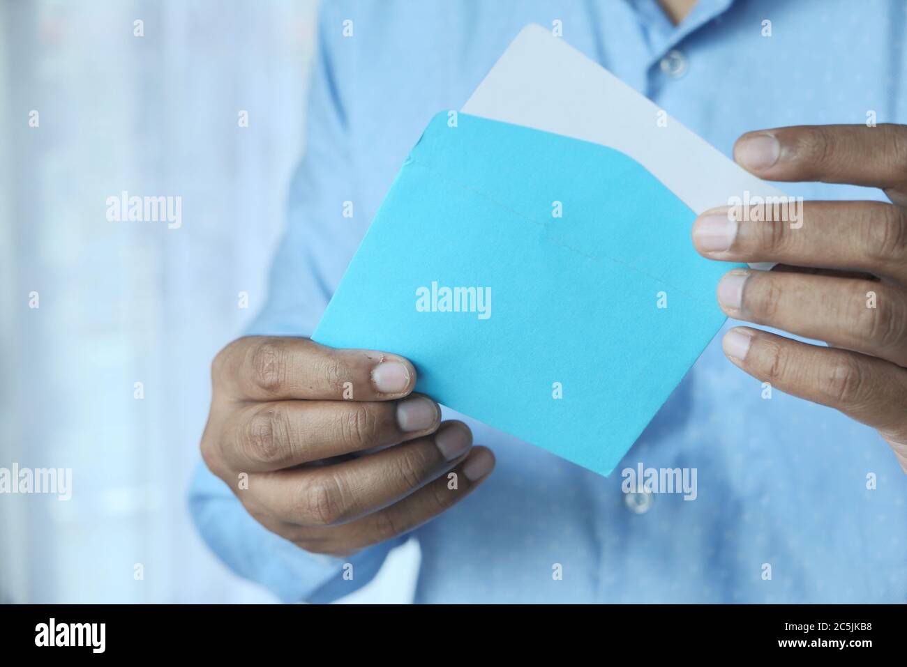 Nahaufnahme der Hand mit blauem Umschlag. Stockfoto
