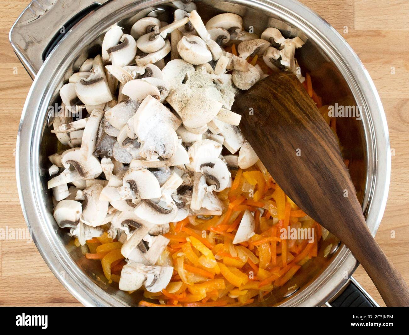 Champignons, Zwiebeln und Karotten in Scheiben geschnitten. Frittieren Sie die Speisen. Metallutensilien mit Zutaten, Draufsicht. Stockfoto