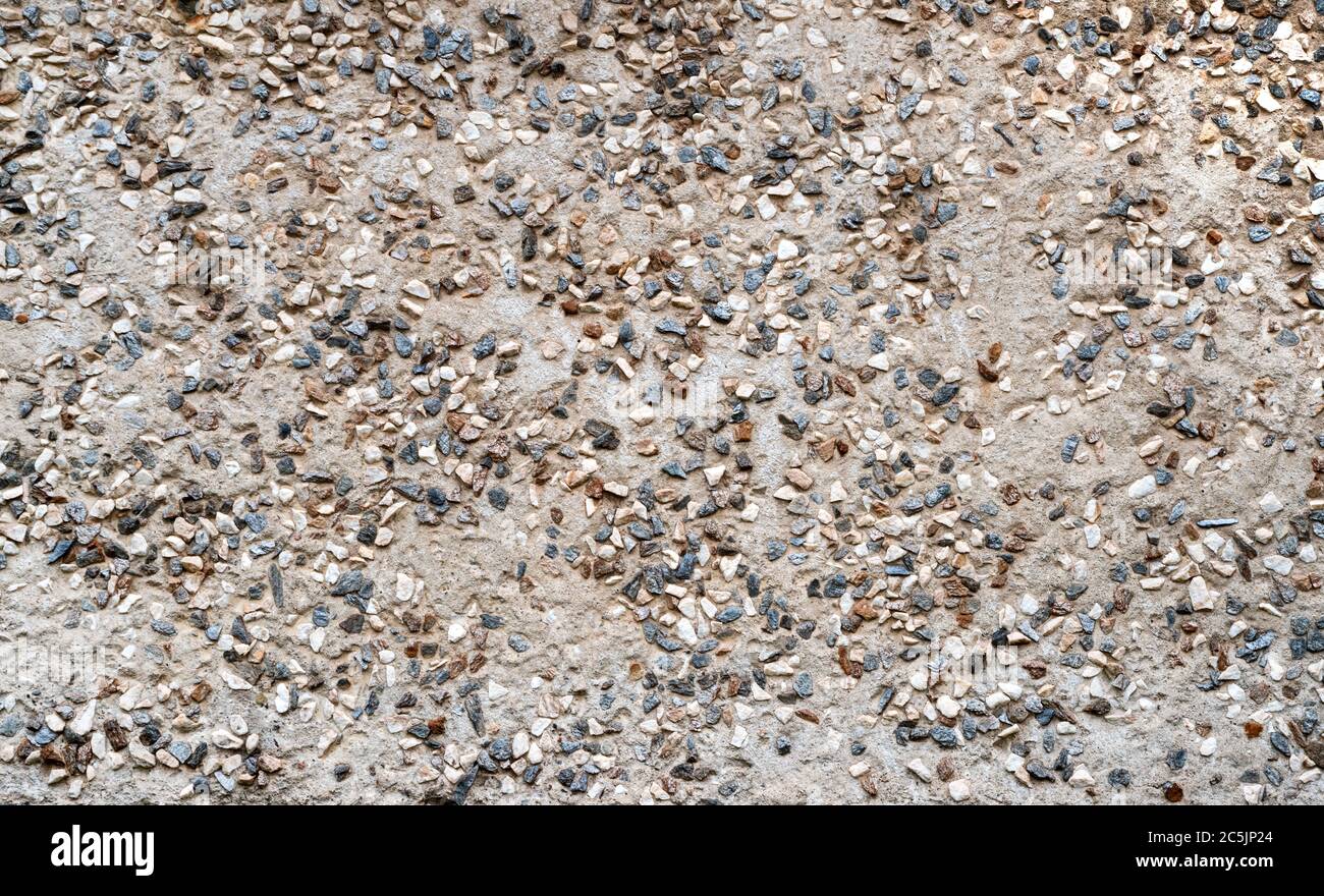 Textur Wandbeschichtung von Steinen. Hauswand Außenputz. Abstrakter Hintergrund Pflaster bestehend aus kleinen Kieselsteinen in Zement eingebettet Stockfoto