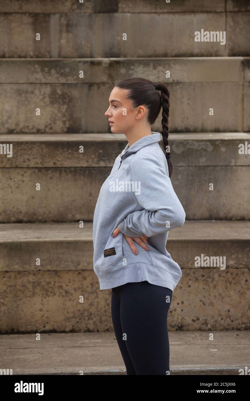 Eine sportliche junge Frau, die Sportkleidung trägt, die vor einer Reihe von Schritten steht und bereit für die Übung ist. Stockfoto