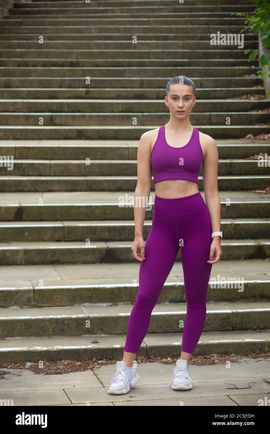Eine attraktive junge Frau in Sportkleidung, die vor einer Reihe von Schritten steht, bereit für Bewegung. Stockfoto