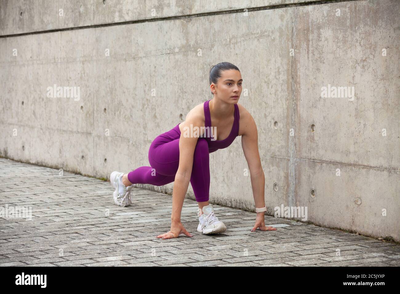 Junge Frau, die ihre Beine vor einem Training streckt. Stockfoto
