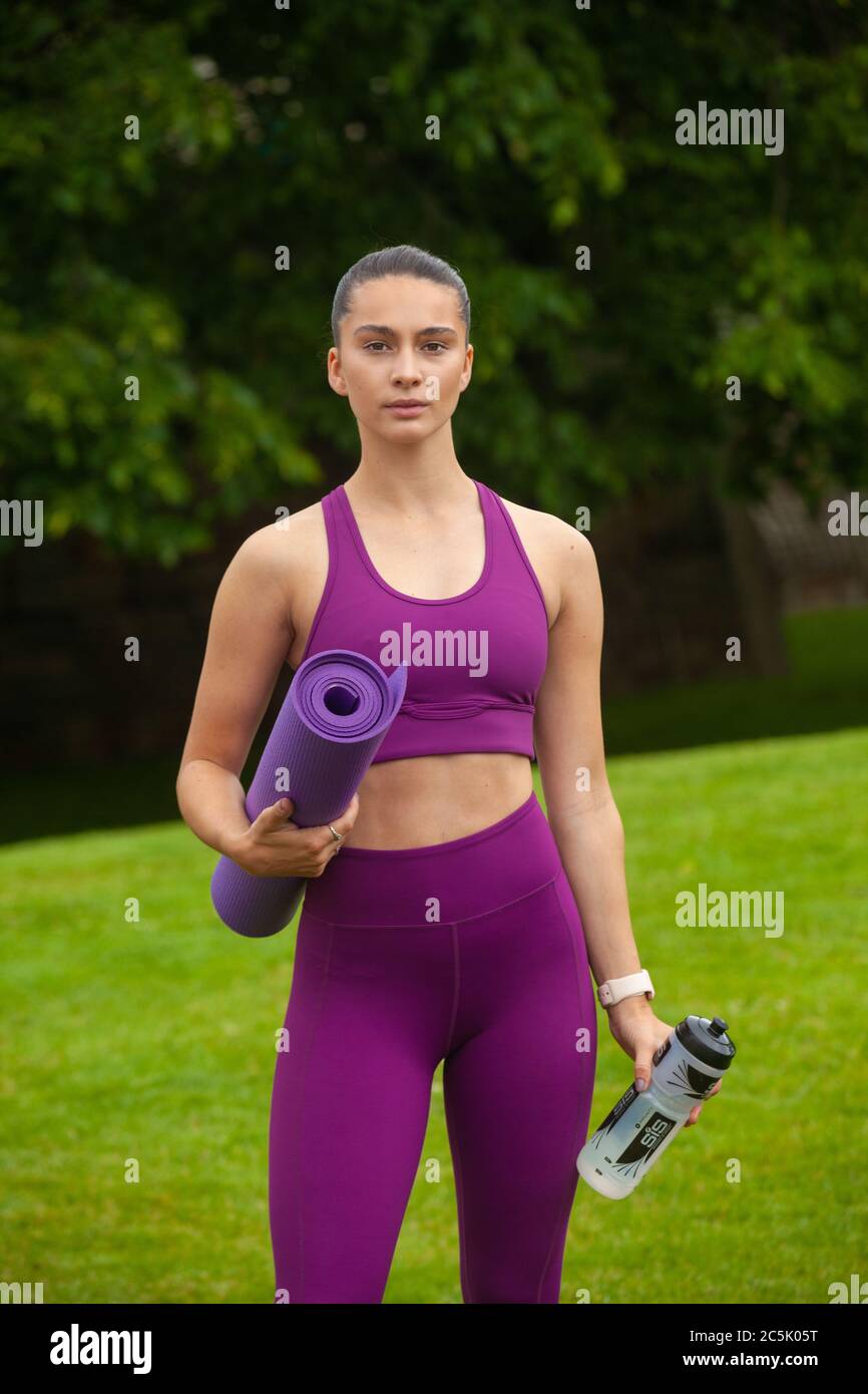 Porträt einer athletischen jungen Frau in Leggings und Sport-BH mit einer Übungsmatte Stockfoto