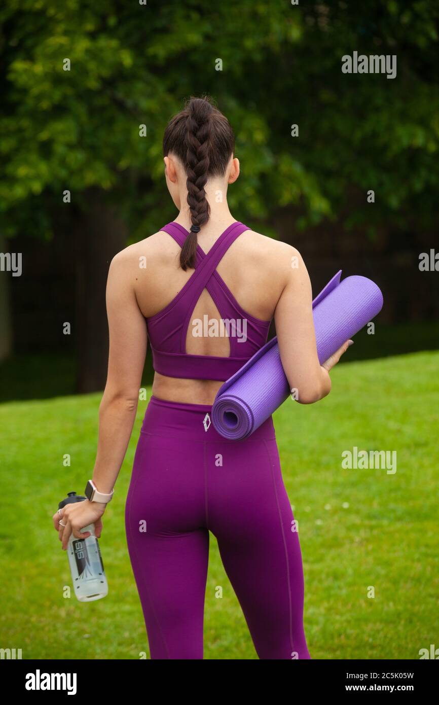 Eine Rückansicht einer athletischen jungen Frau in Leggings und Sport-BH mit einer Trainingsmatte Stockfoto