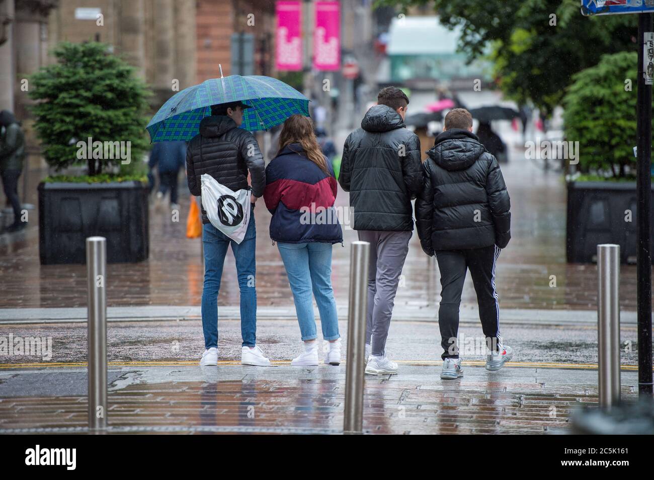 Glasgow, Schottland, Großbritannien. Juli 2020. Im Bild: Buchanan Street Shopping-Bereich mit Käufern trotzen dem strömenden Regen mit Regenschirmen und Gesichtsbezügen, die am 10. Juli nächste Woche obligatorisch werden. Quelle: Colin Fisher/Alamy Live News Stockfoto