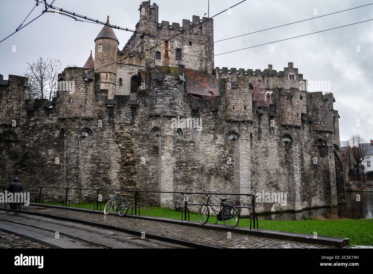 Das mittelalterliche Schloss der Grafen im Zentrum der Stadt während regnerischen Tag. Nasse Straße und Fahrräder im Vordergrund. Stockfoto