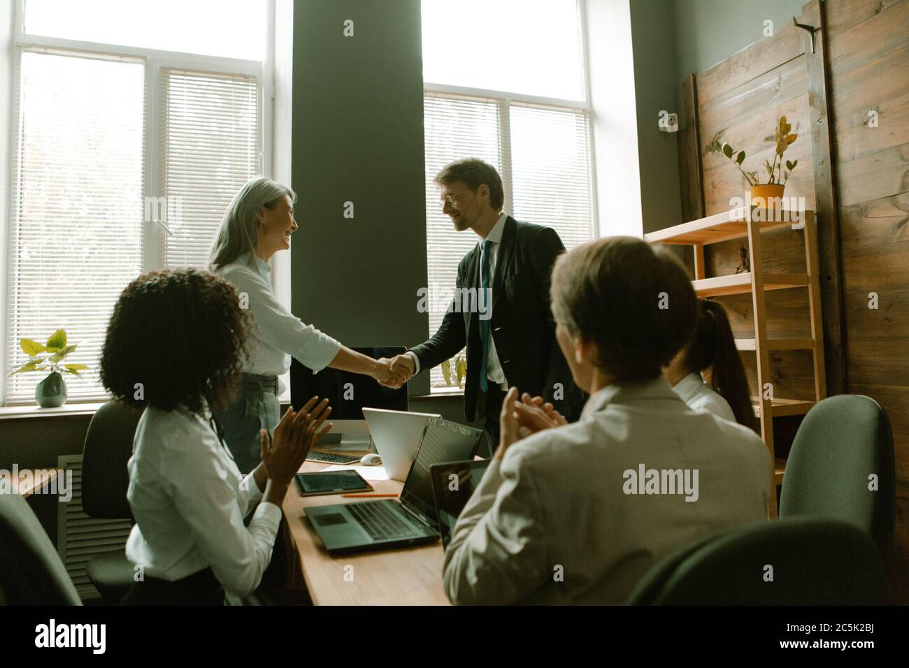 Handschlag der Führer zum Applaus der Kollegen. Geschäftsleute schütteln sich die Hände. Teamarbeit im Büro. Getöntes Bild Stockfoto