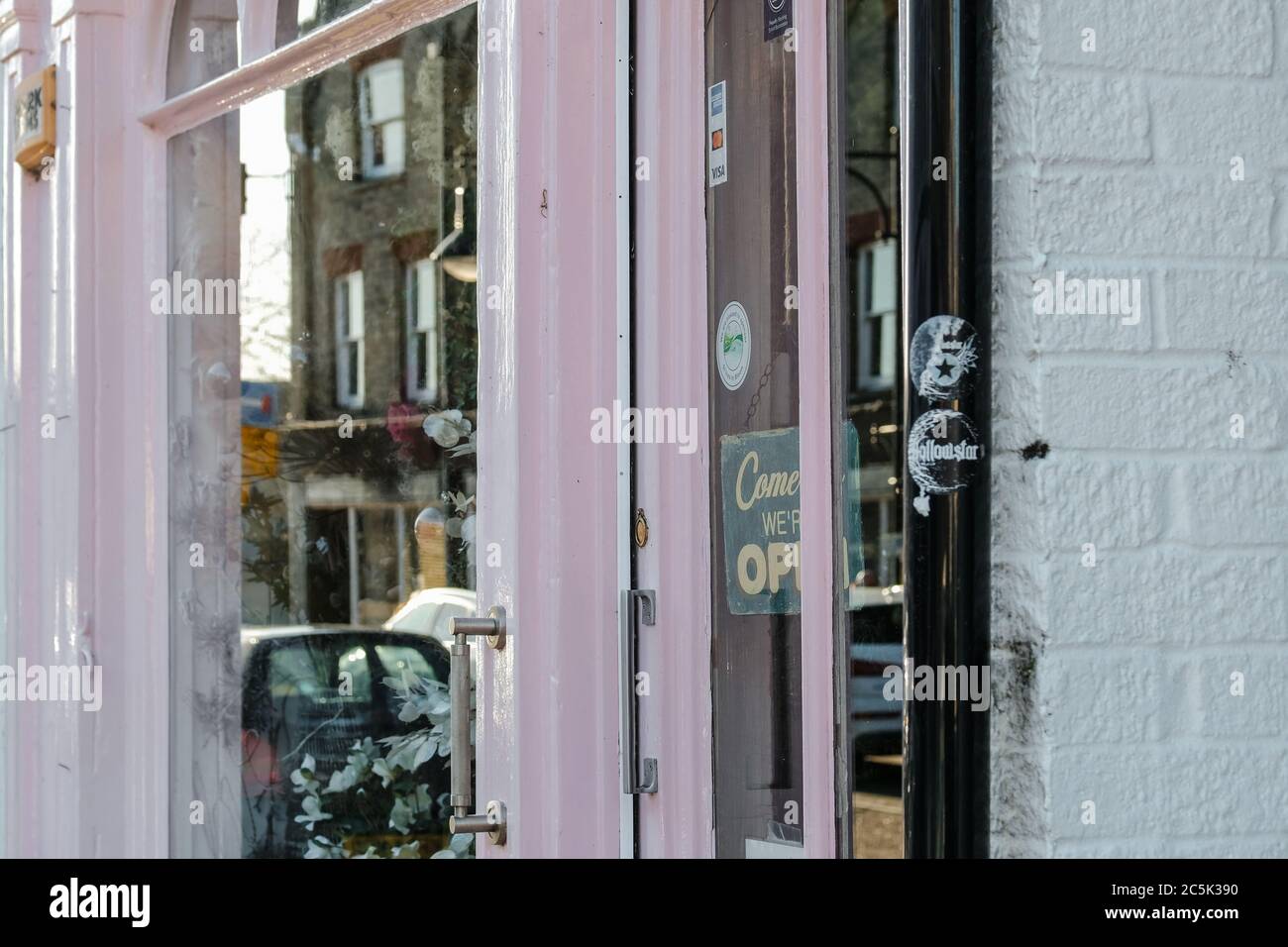 Nahaufnahme eines kleinen Einkaufsbudes vor der Eingangstür. Das  pinkfarbene Schaufenster spiegelt das Geschäft in dieser belebten Straße  wider Stockfotografie - Alamy