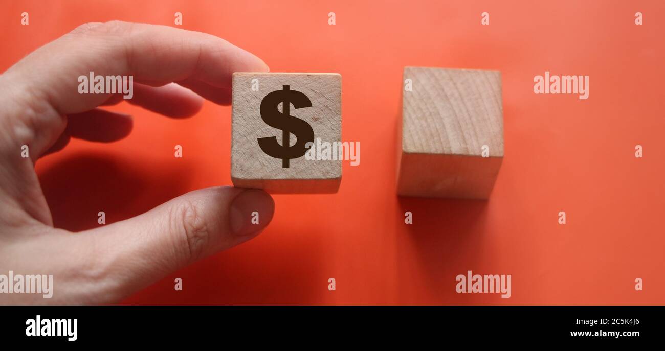 Holzblock mit dem US Dollar-Symbol in der Hand hält es und ein weiterer leerer. Roter Hintergrund. Geschäftskonzept der Gewinnchoise Stockfoto