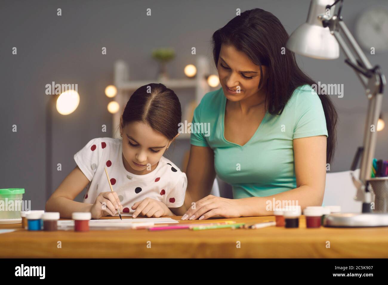 Kreativität und Entwicklung des Kindes. Glückliche Familie Mutter und Tochter zeichnen Farben am Tisch zu Hause. Stockfoto