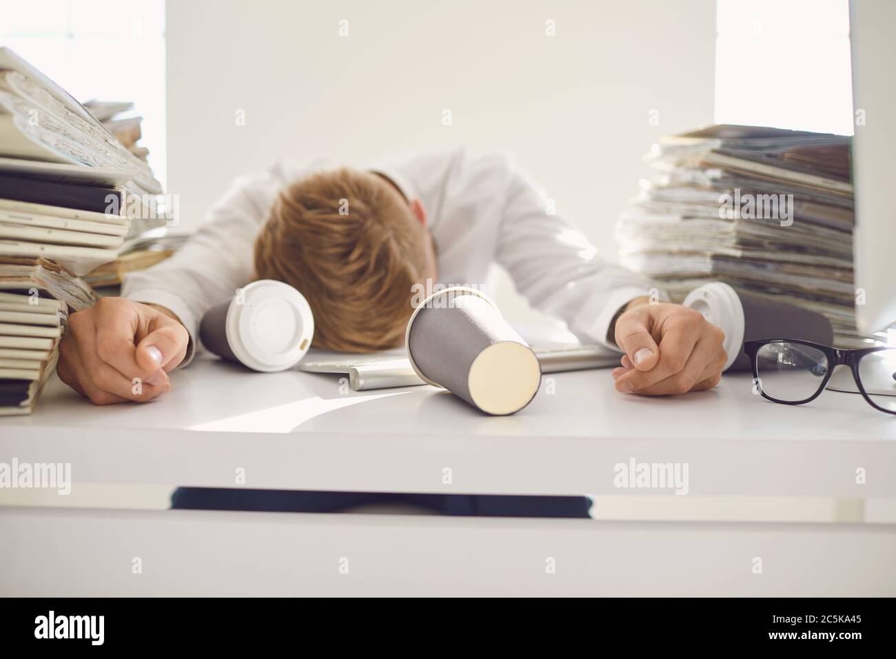 Müde beschäftigte Geschäftsleute, die mit einem Computer an einem Tisch schlafen. Stockfoto