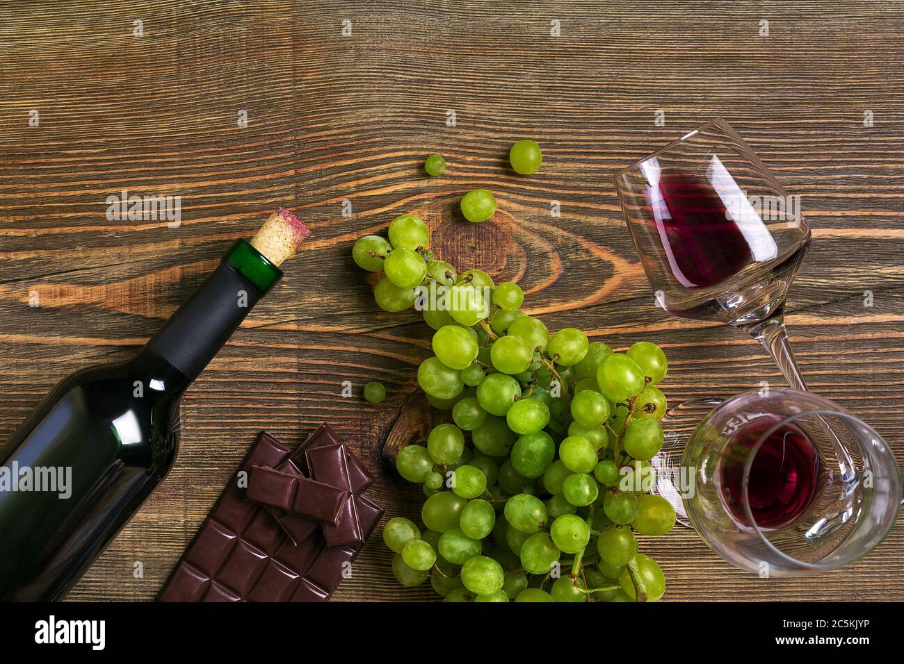Zwei Gläser, eine Flasche Rotwein und Weintraube auf einem Holztisch Stockfoto