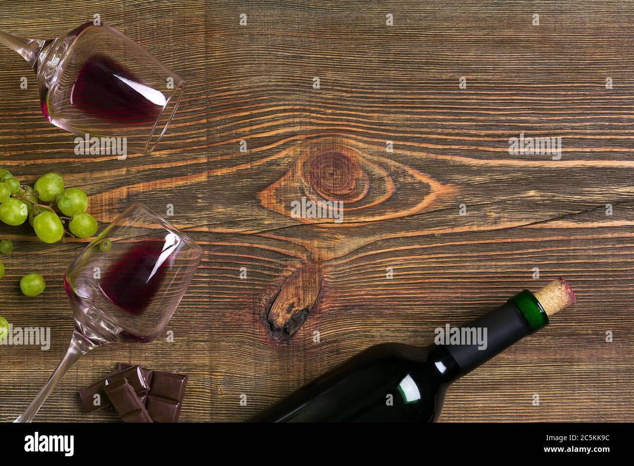 Zwei Gläser, eine Flasche Rotwein und Weintraube auf einem Holztisch Stockfoto