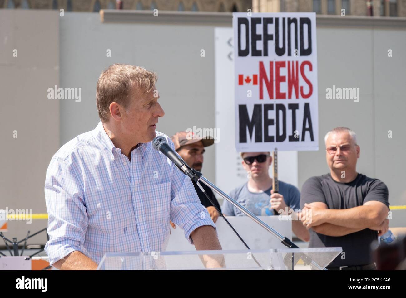 Maxime Bernier von der Volkspartei Kanadas hält eine Rede auf einem Canada Day Protest am Parliament Hill, während ein Protestler die Mainstream-Medien anprangert. Stockfoto