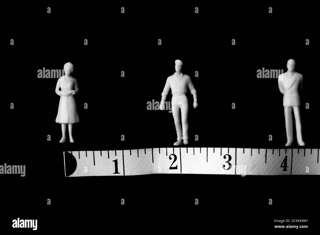 Covid-19, soziale Distanz, Konzept. Figuren von Männern und Frauen und ein Meter auf schwarzem Hintergrund mit Platz für Botschaft. Stockfoto