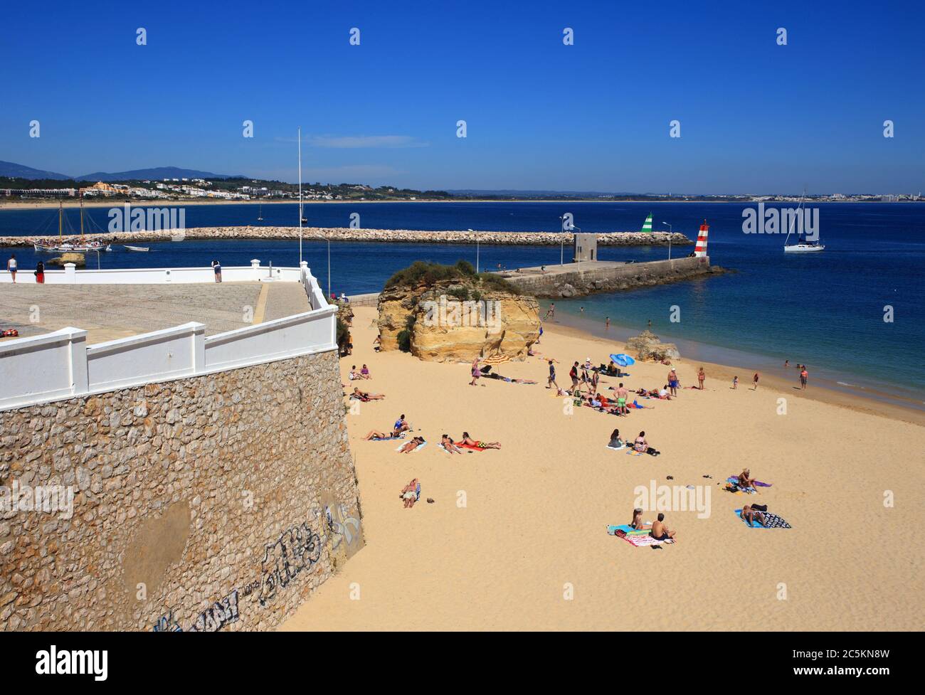 Lagos, Algarve, Portugal. Blick auf die Klippen von Touristen, die sich in der warmen Sonne am Stadtstrand in Lagos, in der westlichen Algarve sonnen. Stockfoto