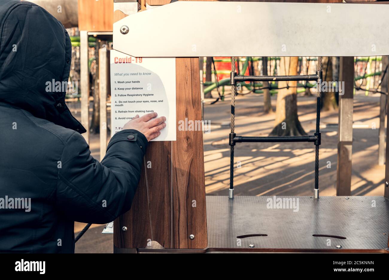 Notieren Sie covid-19, was Sie wissen müssen. Auf einem leeren Spielplatz in einem Park hängen. Selbstisolierung und Quarantäne bei einer Pandemie. Stockfoto