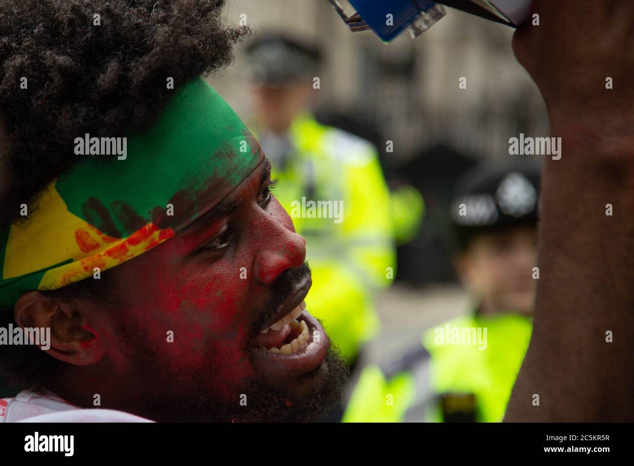 Ein Protestler mit roter Farbe im Gesicht während der Demonstration.die äthiopische Oromo-Gemeinschaft in London protestiert gegen den ermordeten Sänger Haacaaluu Hundeessaa. Haacaaluu sang in der Oromo-Sprache, Äthiopiens größter Volksgruppe, und seine Musik wurde zur Melodie einer Protestbewegung, die 2018 dazu beitrug, die äthiopische Regierung zu zerfallen. Stockfoto