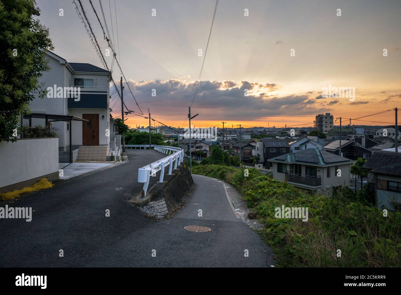 Enge Straße den Hügel hinauf führt zu Blick auf japanische Nachbarschaft und wunderschönen Sonnenuntergang Stockfoto