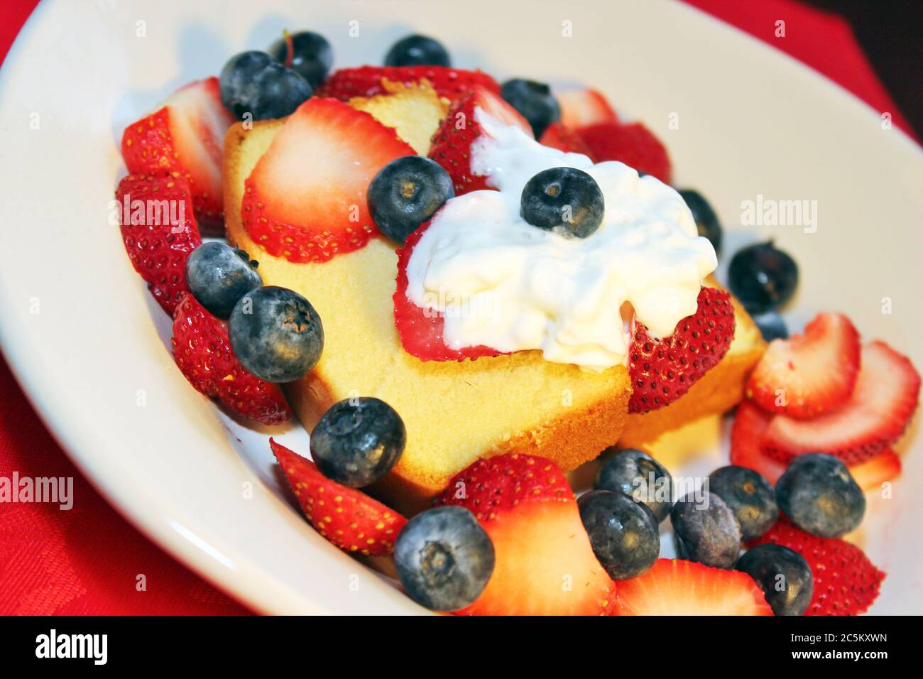 Kuchen mit frisch geschnittenen Erdbeeren, Heidelbeeren und Schlagsahne Belag Stockfoto