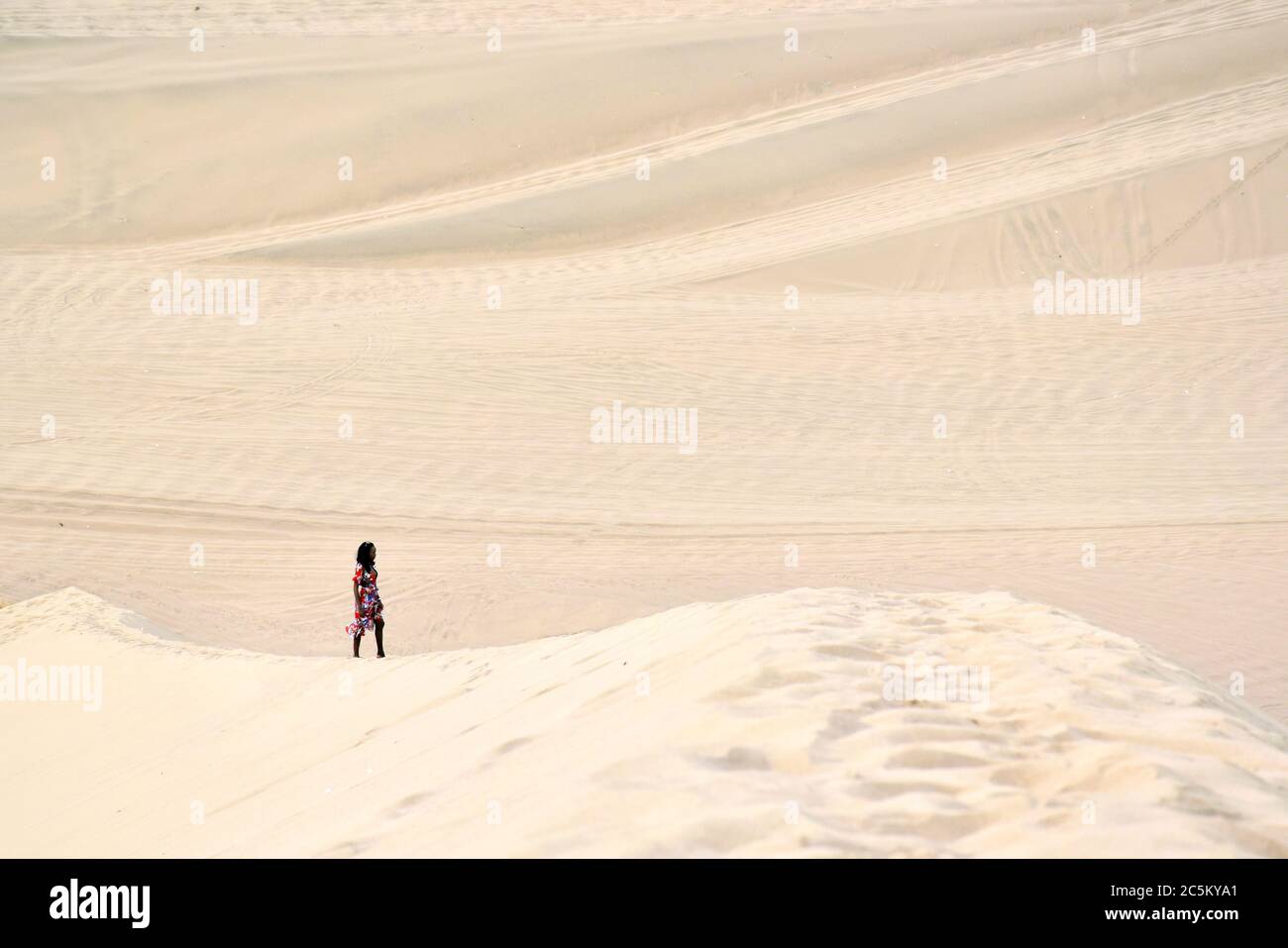 Frau in der Ferne posiert auf Sanddünen in Huacachina, Peru Stockfoto