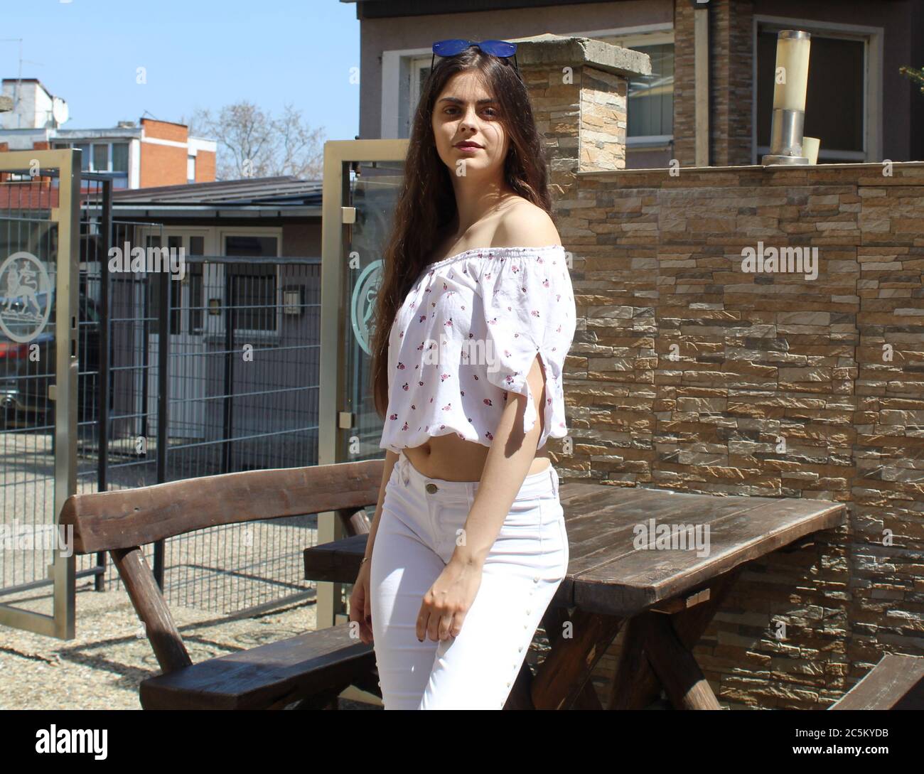 Langhaarige Mädchen mit weißen Hosen posiert im Freien Stockfoto