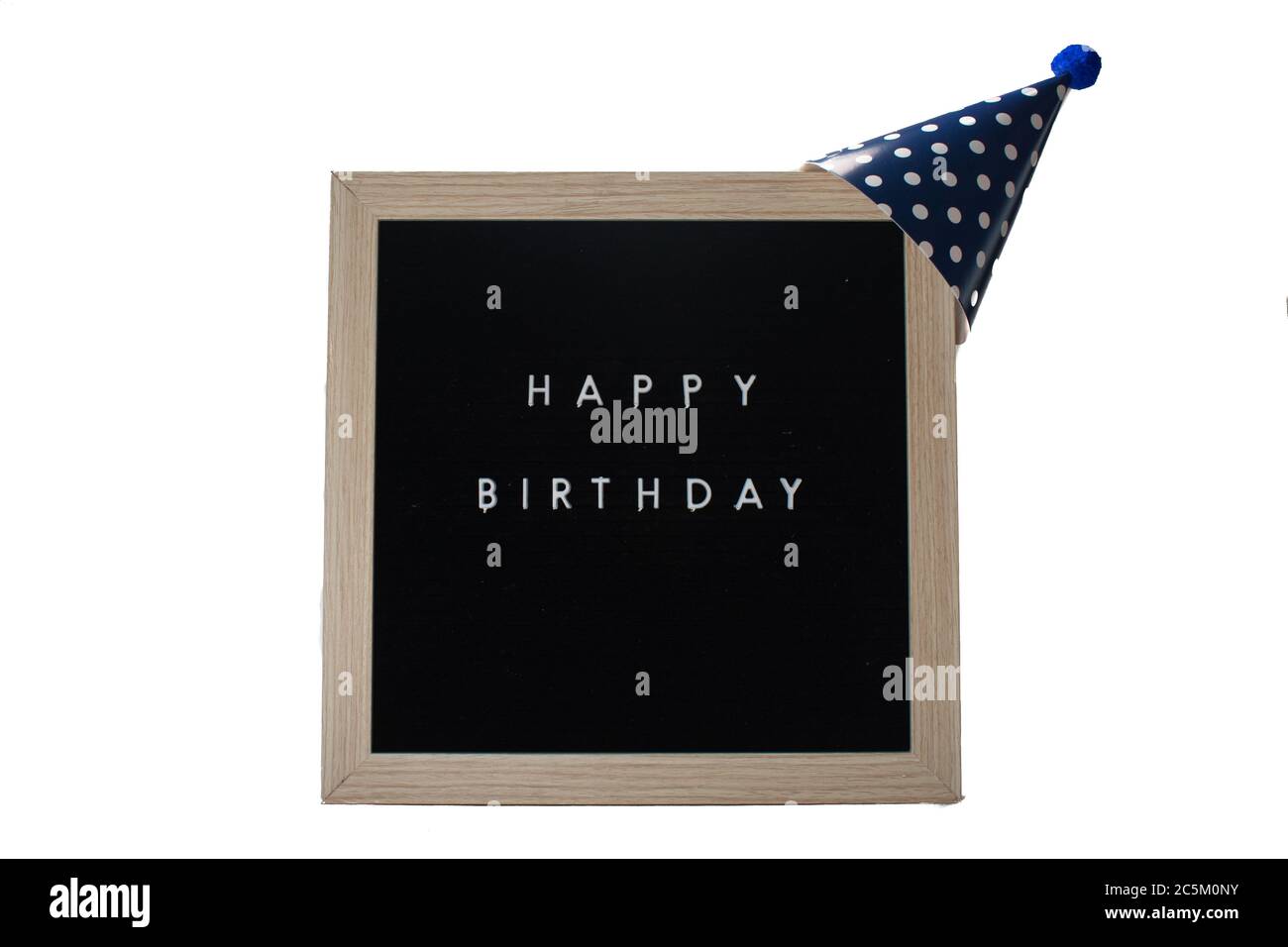 Ein schwarzes Schild mit Birkenrahmen, der alles gute zum Geburtstag sagt, mit einem dunkelblauen Hut mit Polka-Punkten und einem blauen Baumwollball auf dem Oberteil auf einem rein weißen Rücken Stockfoto