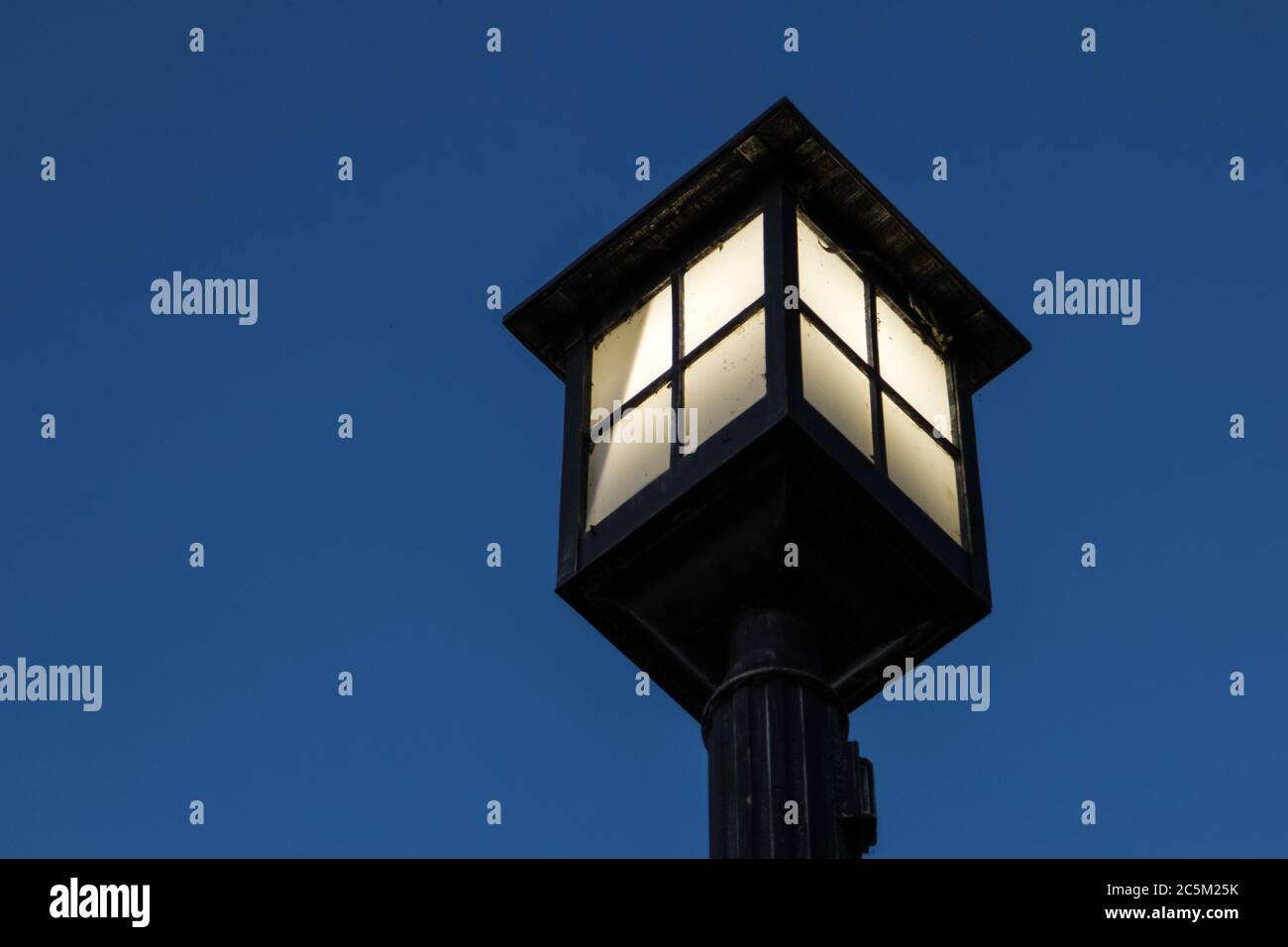 Beleuchtete Vintage Street Lamp. Schwarzer Lampenpfosten mit Kopierraum beleuchtet. Stockfoto