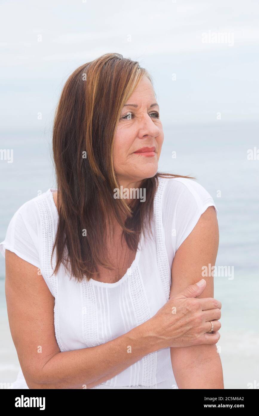 Portrait Attraktive reife Frau allein im Freien, mit traurigen und besorgt Gesichtsausdruck, mit verschwommenem Hintergrund. Stockfoto