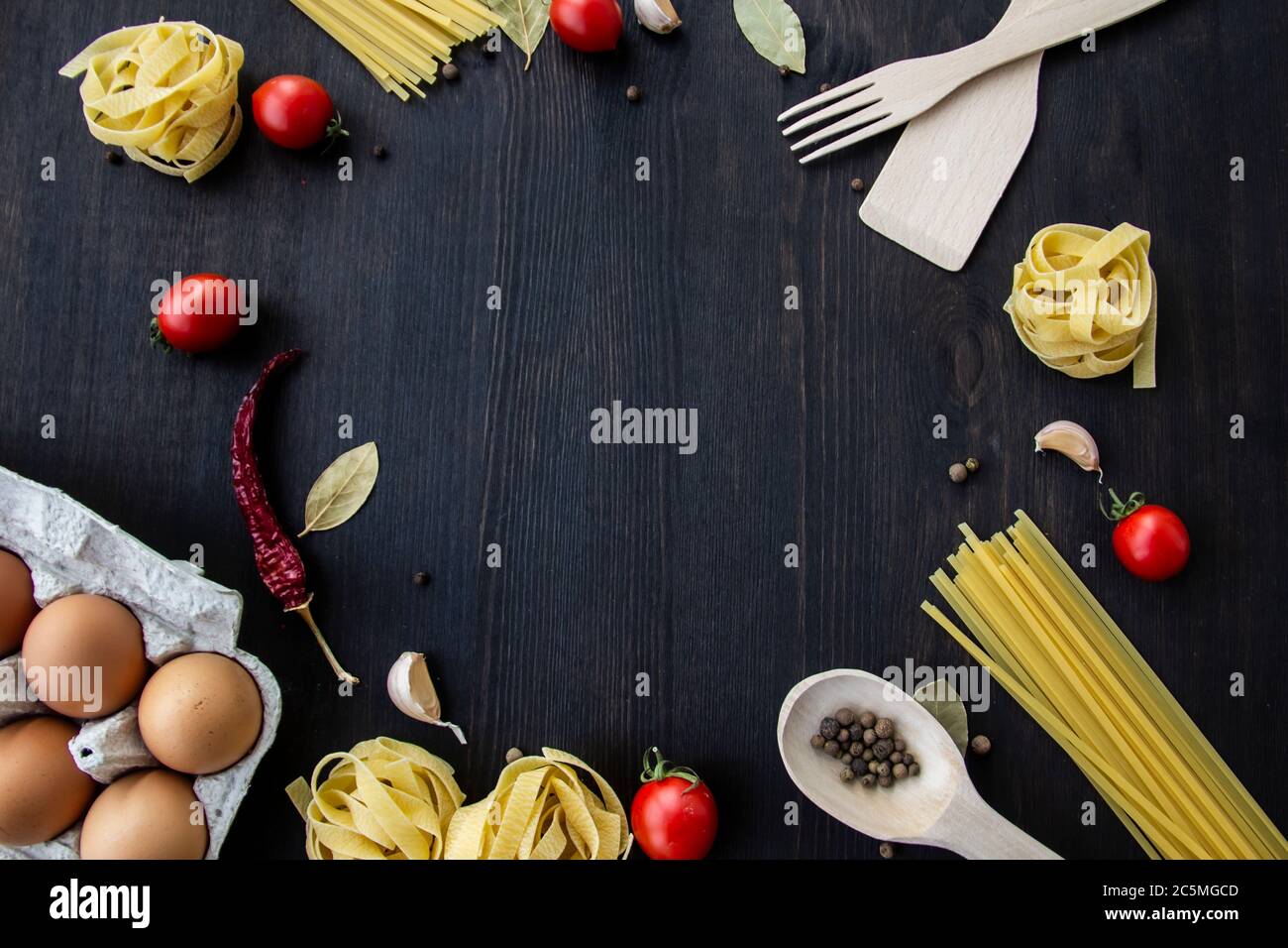 Kochen Lebensmittel Hintergrund mit freiem Platz für Text. Zusammensetzung mit Spaghetti, Tomaten, Eiern, Knoblauch, Lorbeerblatt über dem Holzhintergrund. Zutaten für Stockfoto