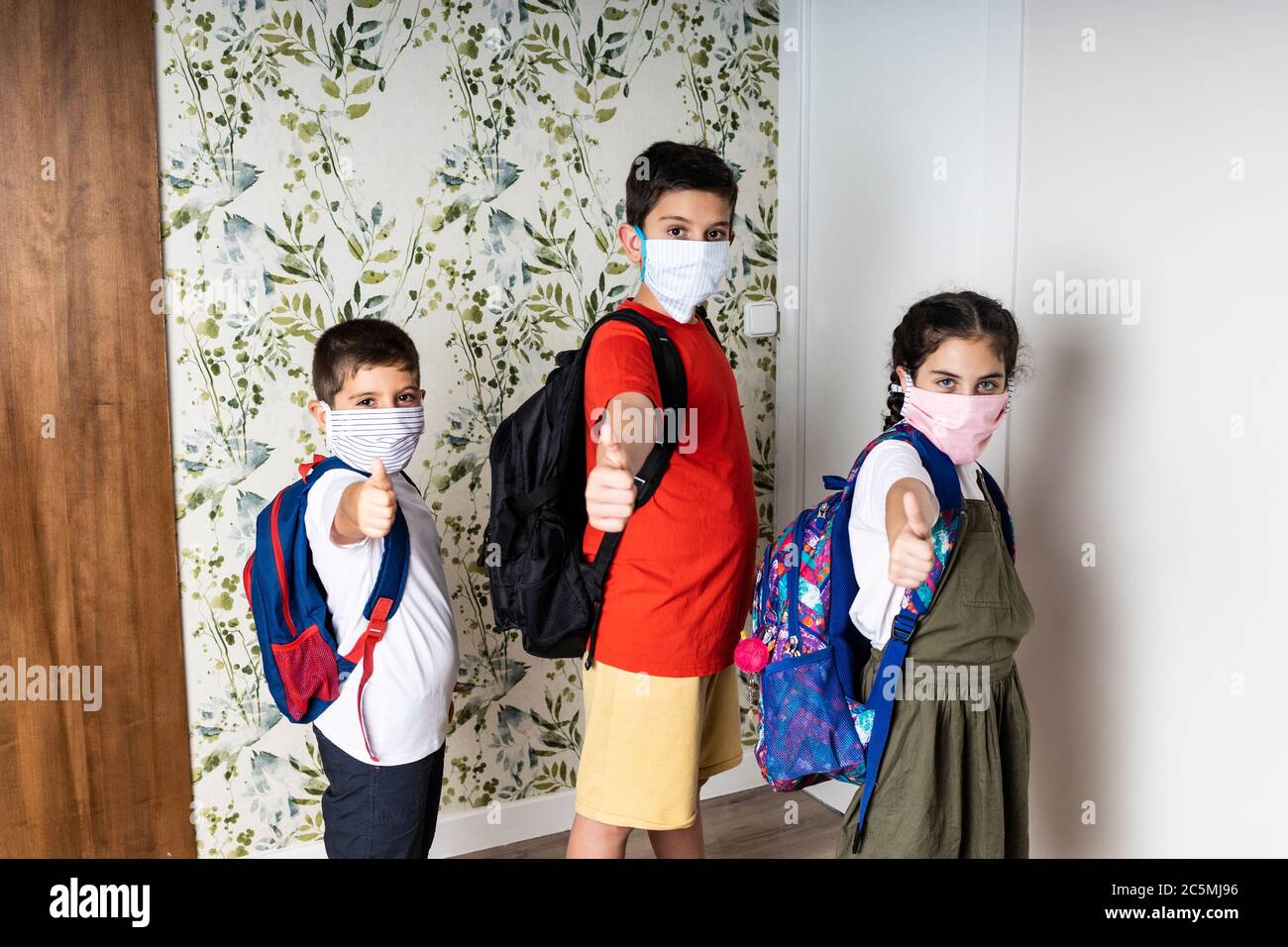 Drei Kinder mit Gesichtsmasken, bevor sie zur Schule gehen Stockfoto