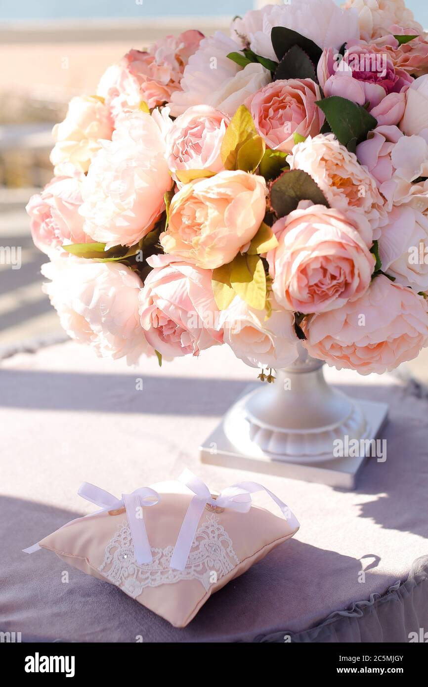 Rosa Rosen in Vase neben kleinen Kissen auf dem Tisch. Stockfoto