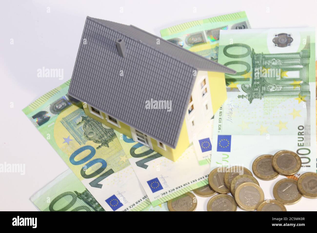 Modellhaus mit (Euro)Banknoten und Münzen als Symbolbild für hohe Immobilienpreise Stockfoto
