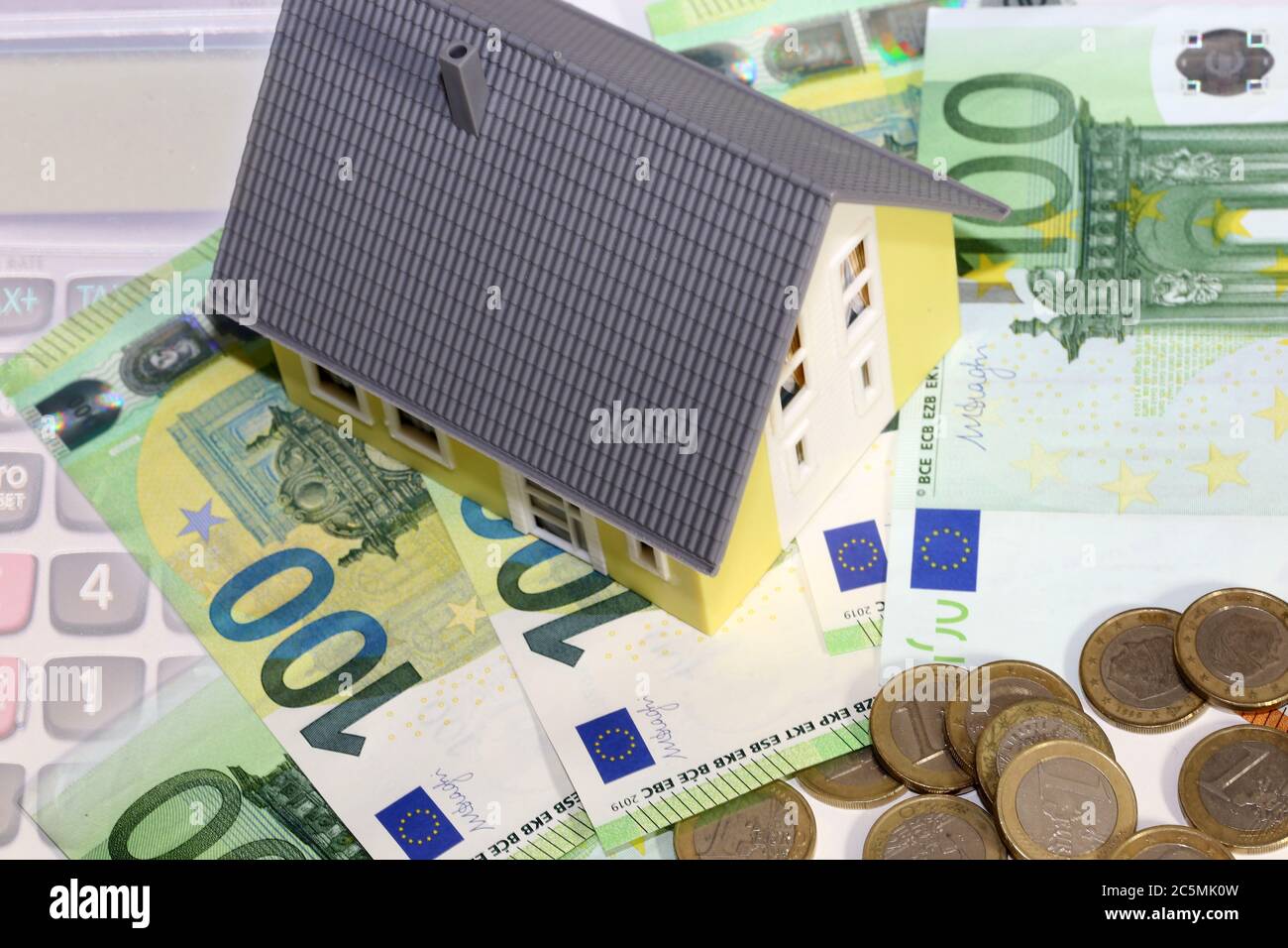 Modellhaus mit (Euro)Banknoten und Münzen als Symbolbild für hohe Immobilienpreise Stockfoto