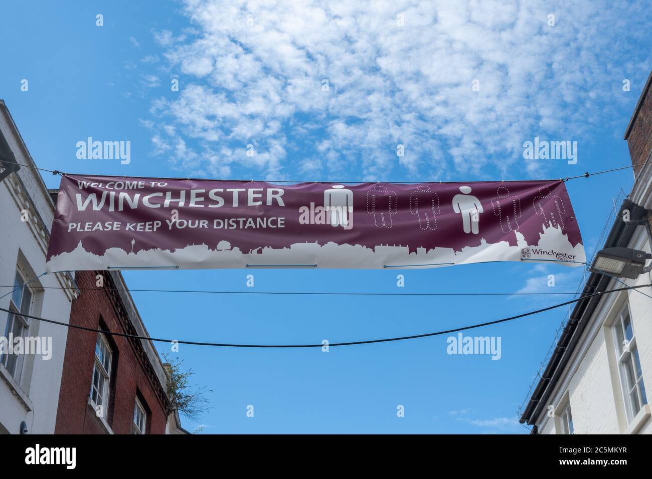 Banner mit der Aufforderung, „bitte Abstand halten“, soziales Distanzierungsschild, gegenüber Winchester High Street, Hampshire, Großbritannien Stockfoto