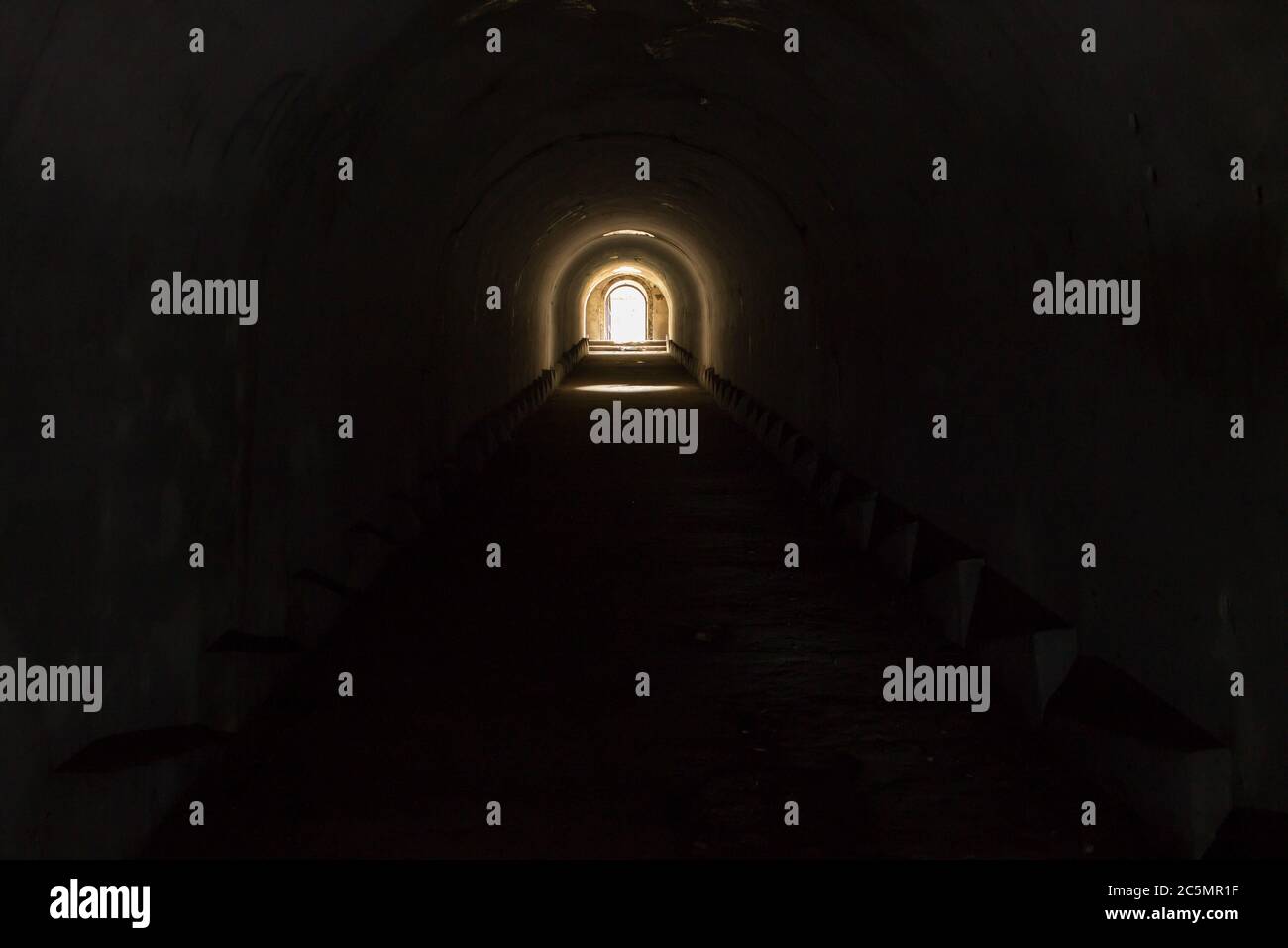 Eine beleuchtete Tür, die zur Freiheit von einem düsteren dunklen unterirdischen Durchgang am Fort Pospelov in Wladiwostok führt. Stockfoto