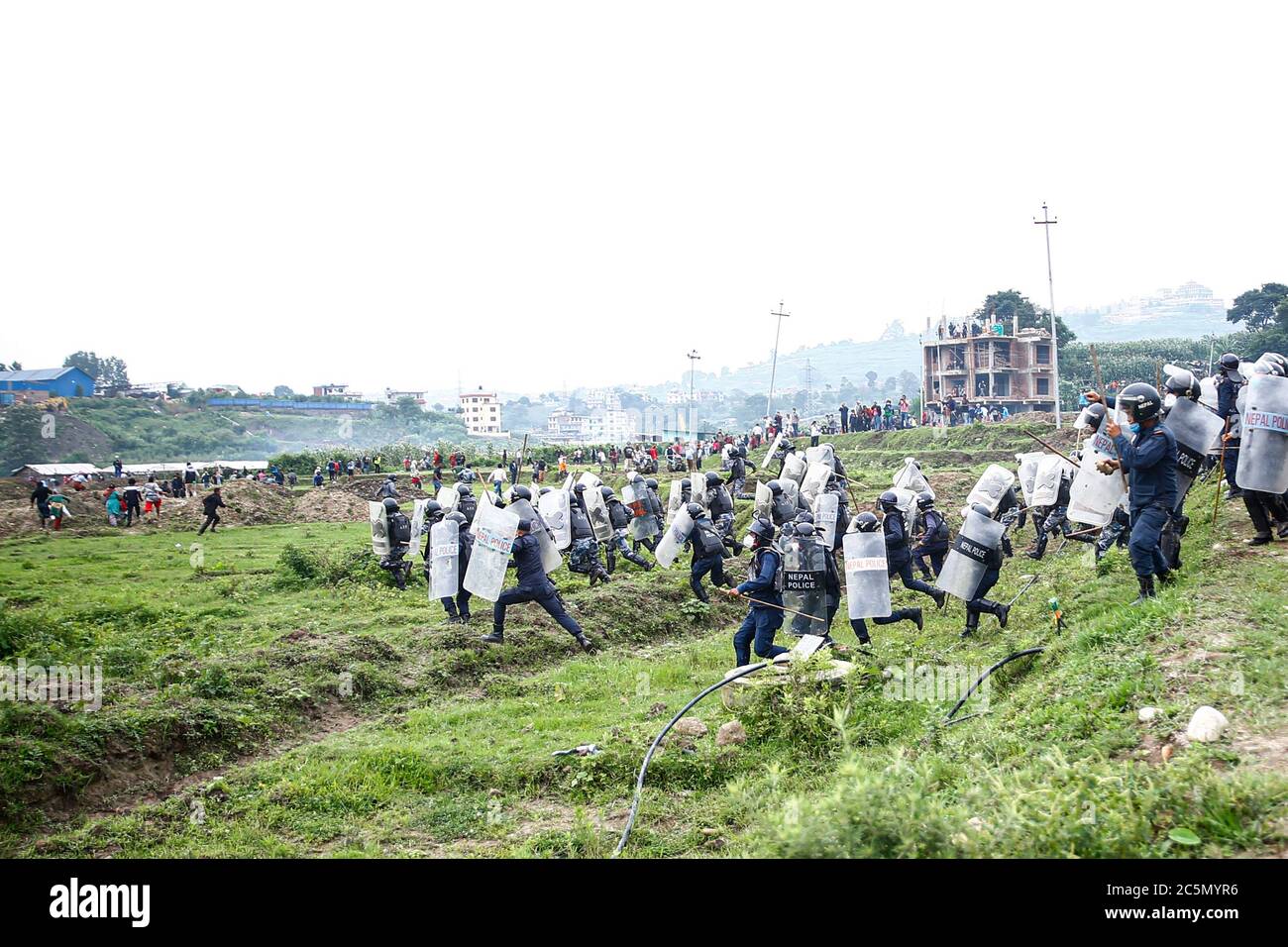 4. Juli 2020, Lalitpur, Nepal: Polizei verfolgt Demonstranten, die Steine auf die Polizei werfen, nachdem Einheimische aus Kathmandu, Bhaktapur und Lalitpur bei einem Protest im Namen des 76.2 Kilometer langen Schnellstraßenprojekts, das von Khokana in Lalitpur bei Khokana in Lalitpur startet, mit bewaffneten Polizeikräften und Riot-Polizeikräften zusammenstoßen. Nepal am Samstag, den 4. Juli 2020. Die indigenen Newar-Gemeinden Khokana und Bungamati sind besorgt über den Schaden, den die Fast Track-Konstruktion ihrem Eigentum, Land und kulturellen Rechten zufügen könnte. (Bild: © Skanda Gautam/ZUMA Wire) Stockfoto