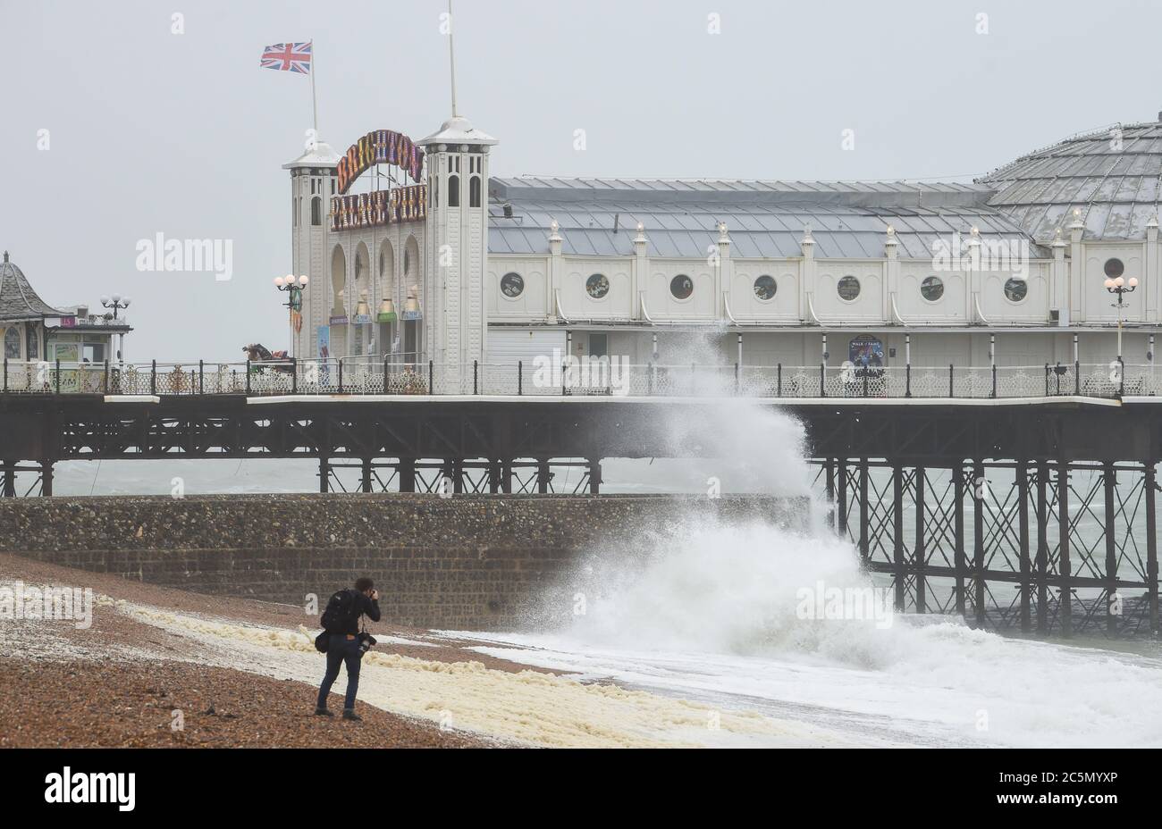 Brighton UK 4. Juli 2020 - Fotograf beobachtet, wie Wellen am Brighton Palace Pier an einem nassen und windigen Tag an der Südküste einstürzen : Credit Simon Dack / Alamy Live News Stockfoto
