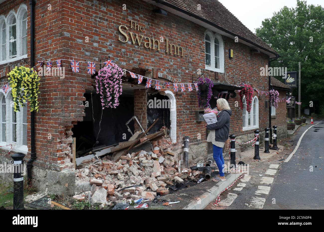 Die Vermieterin des Swan Inn in Ashford, Kent, sieht sich die Schäden an ihrem Pub an, nachdem ein Auto in den frühen Morgenstunden in den Pub abgestürzt ist und ihre Pläne für die Wiedereröffnung zerstört, da die Sperrbeschränkungen für Coronaviren in ganz England gelockert werden. Stockfoto