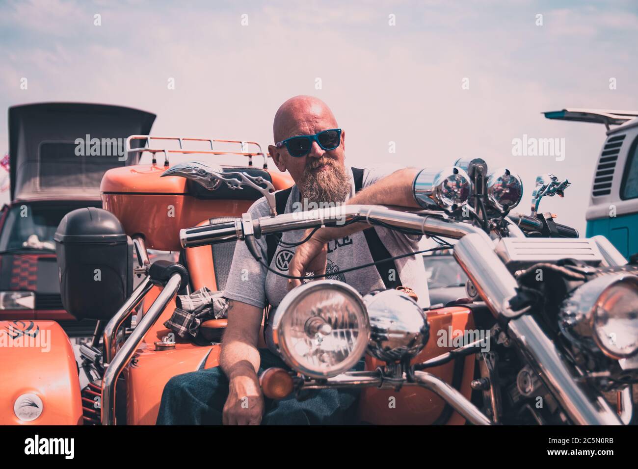 Ein Biker mittleren Alters auf seinem Motorrad mit dem Arm am Lenker Stockfoto