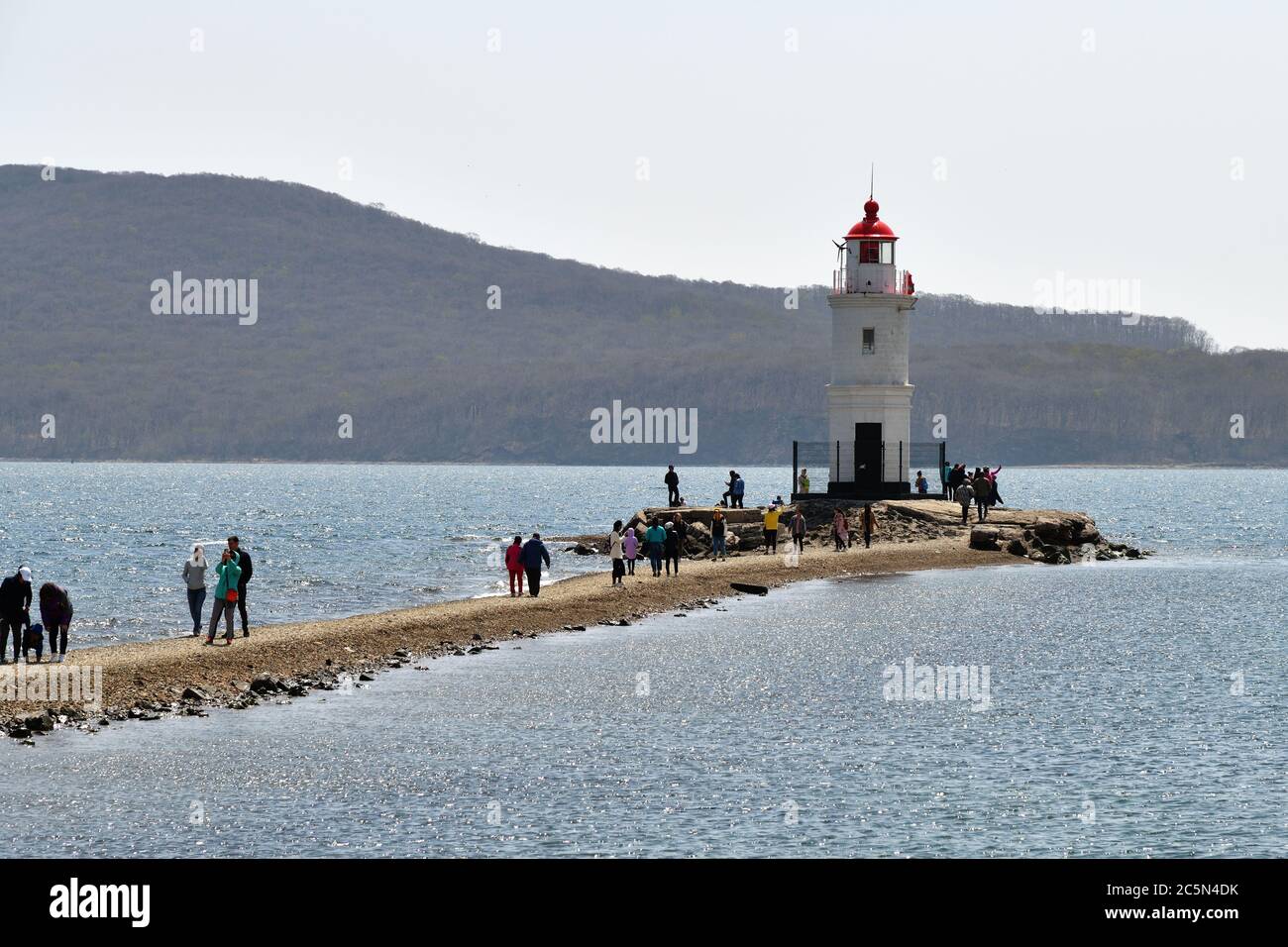 Wladiwostok, Russland - 28. April 2019: Menschen besuchen weißen Leuchtturm mit rotem Dach auf Tokarev Katze. Bosporus Eastern. Region Primorski Stockfoto