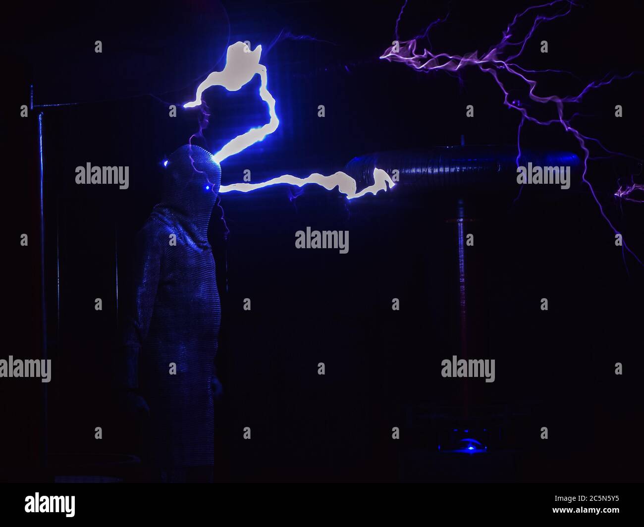 Riesige elektrische Spulen speien Blitz einen Mann in einem Kettenanzug gekleidet schlagen. Elektrische Show Stockfoto