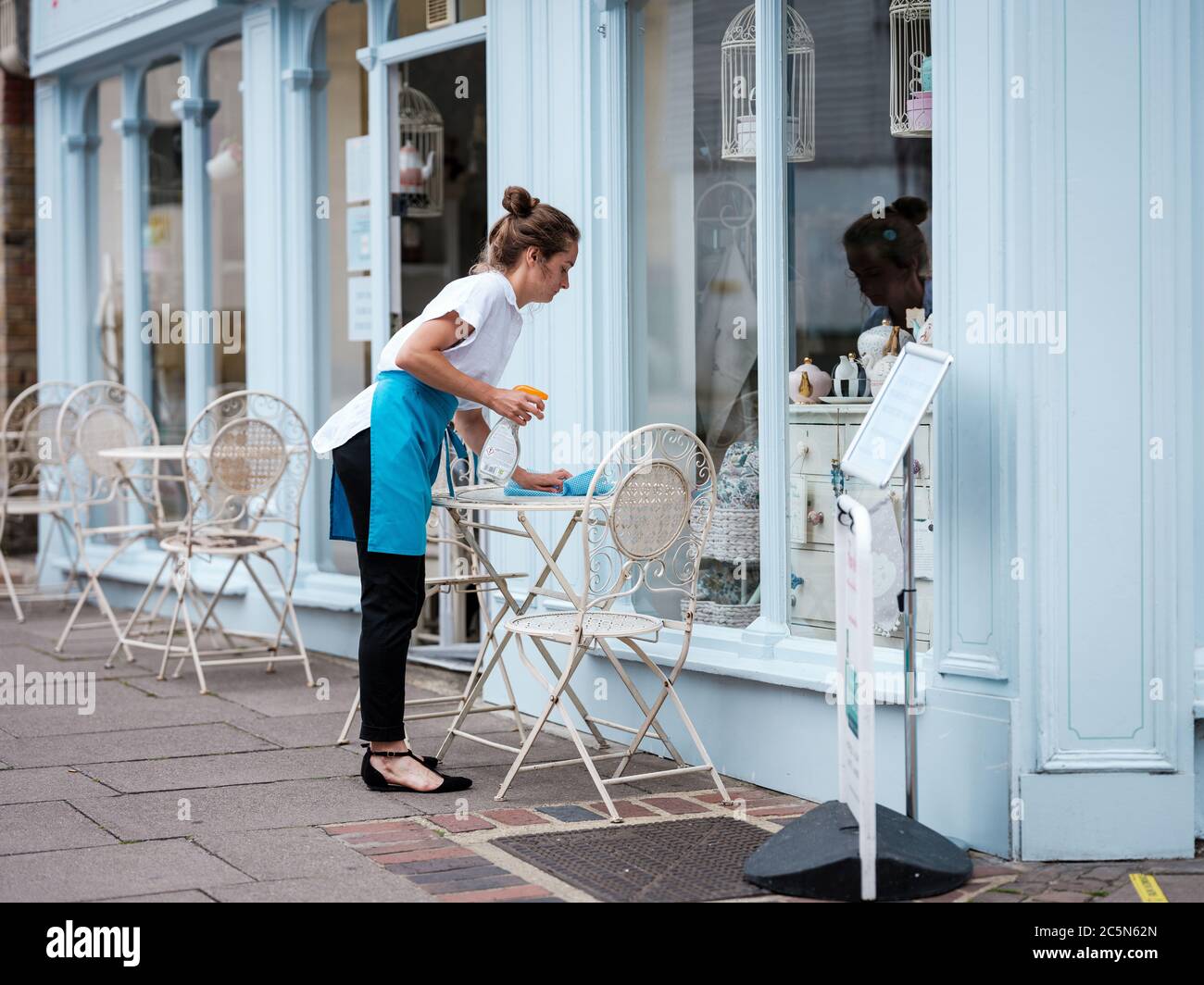 Rochester, Kent, Großbritannien. Juli 2020. Eine Kellnerin putzt einen Tisch vor einem Café auf der Rochester High Street. Die Vereinigten Staaten eröffnen am 4. Juli Pubs, Restaurants, Barbiere, Friseure und Hotels wieder, nachdem sie seit März wegen des Coronavirus-Ausbruchs geschlossen sind. Kredit: Yousef Al Nasser/ Alamy Live Nachrichten Stockfoto